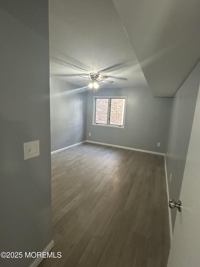 unfurnished room with wood finished floors, a ceiling fan, and baseboards