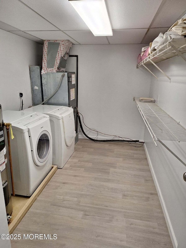 clothes washing area with washing machine and dryer, baseboards, laundry area, and light wood-type flooring