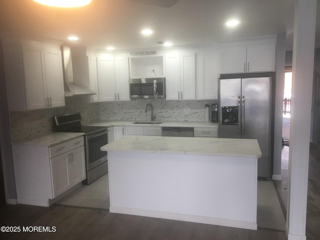 kitchen with wall chimney range hood, tasteful backsplash, stainless steel appliances, and a sink