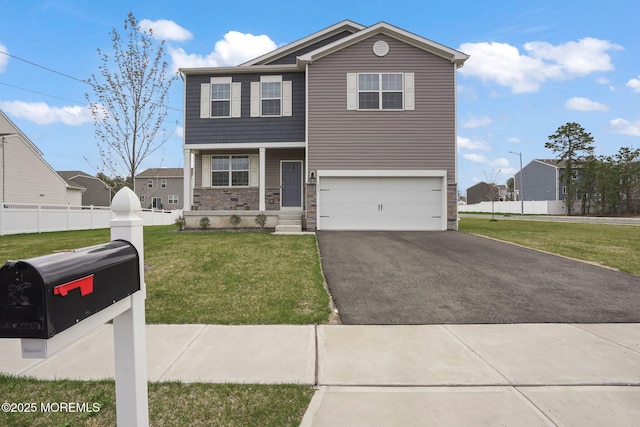 view of front facade featuring driveway, stone siding, an attached garage, fence, and a front yard