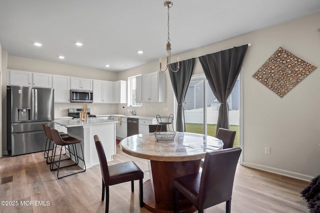 dining room featuring baseboards, recessed lighting, and light wood-type flooring