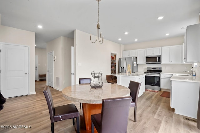 dining space featuring baseboards, visible vents, light wood finished floors, and recessed lighting