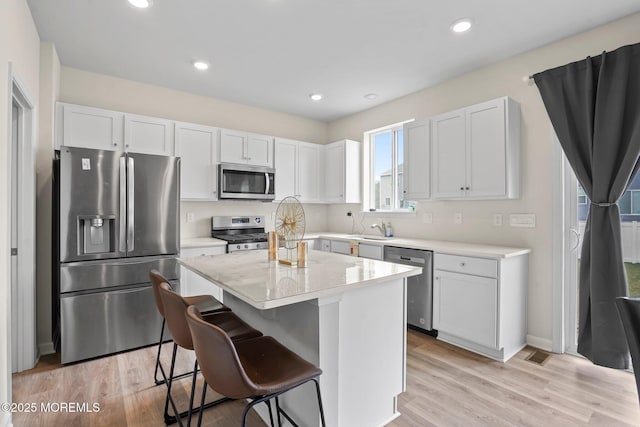 kitchen featuring white cabinets, a kitchen breakfast bar, a center island, and stainless steel appliances
