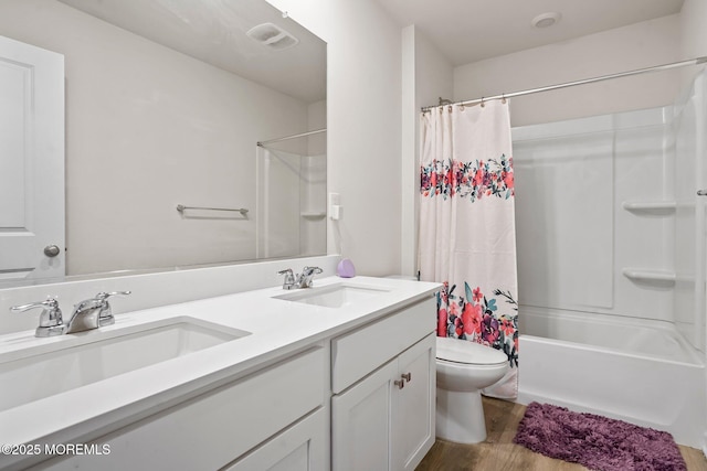 full bath featuring toilet, wood finished floors, a sink, and double vanity