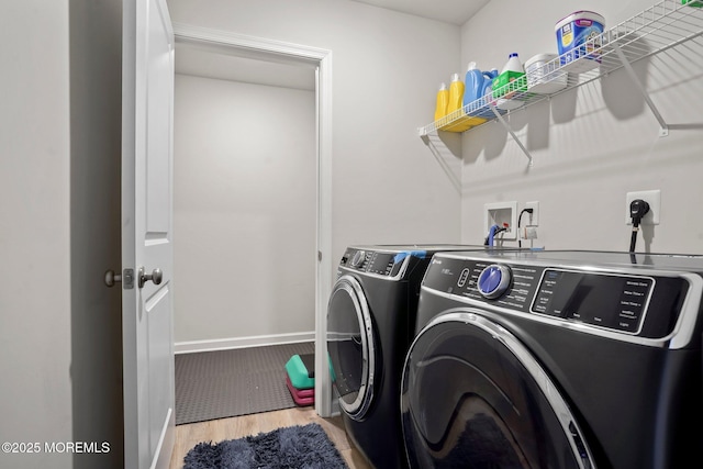 clothes washing area featuring baseboards, wood finished floors, washer and dryer, and laundry area