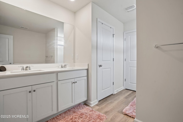 full bath with double vanity, wood finished floors, visible vents, and a sink