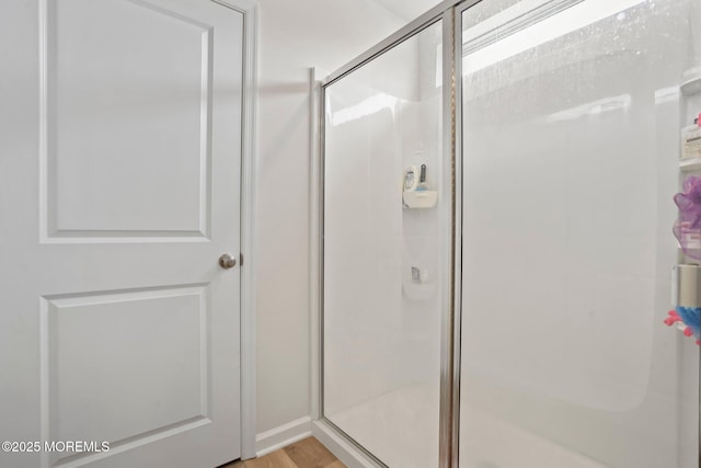 bathroom with wood finished floors and a shower stall