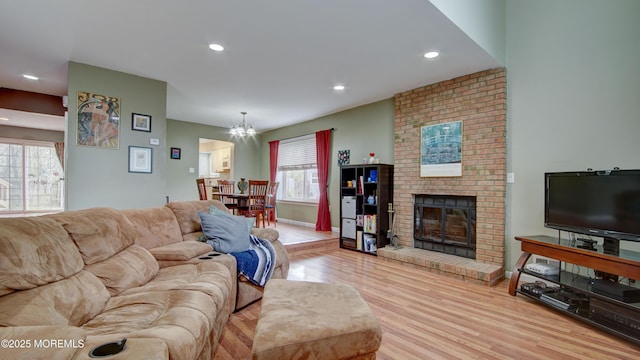 living area with a brick fireplace, recessed lighting, an inviting chandelier, and wood finished floors