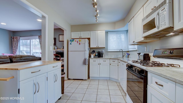 kitchen featuring white cabinetry, light tile patterned flooring, a sink, and white appliances