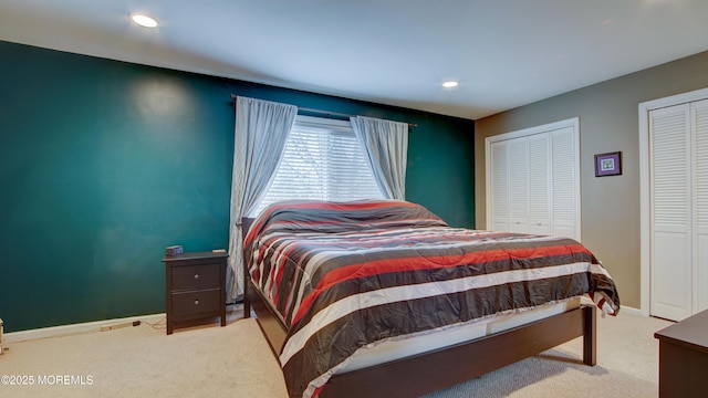 bedroom with two closets, recessed lighting, baseboards, and carpet floors