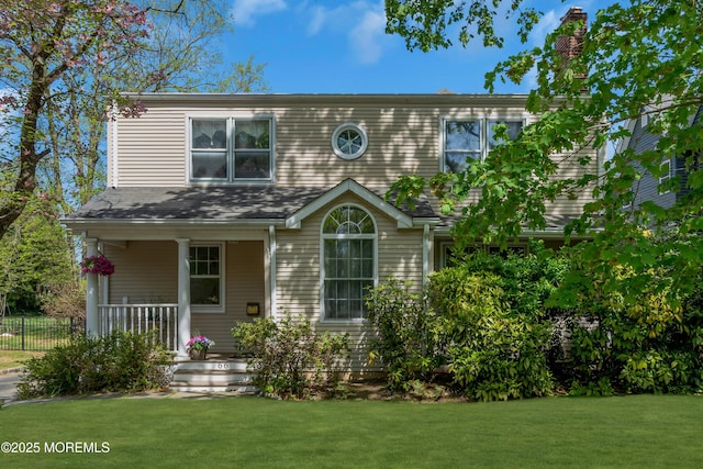 traditional-style home featuring a porch, a chimney, and a front yard
