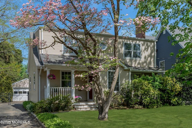 traditional-style house with a garage, a chimney, a porch, and a front yard