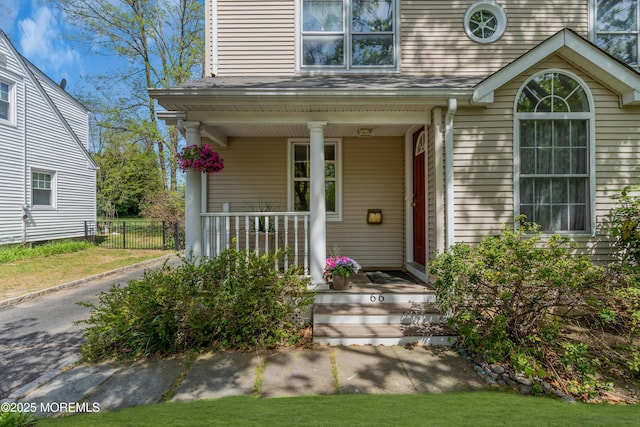 property entrance featuring fence and covered porch