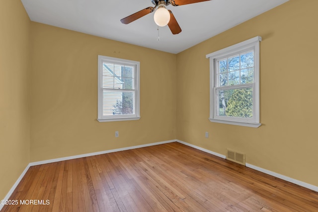 spare room with baseboards, ceiling fan, hardwood / wood-style floors, and visible vents