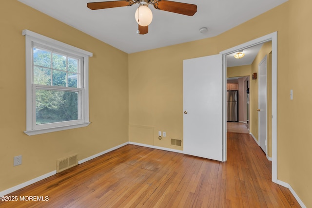empty room featuring visible vents, light wood finished floors, ceiling fan, and baseboards