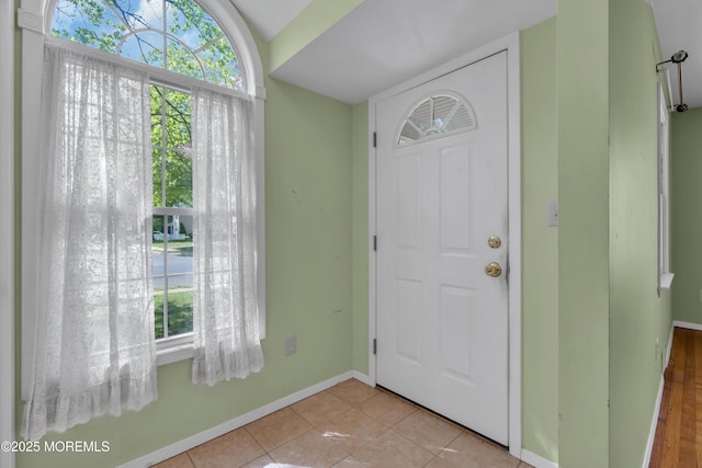 tiled entryway with baseboards and a wealth of natural light