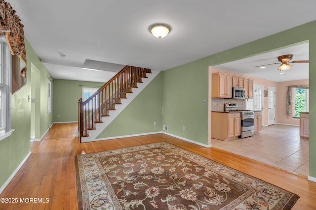living room with baseboards, light wood-style flooring, and stairway