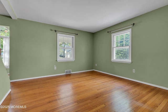 spare room with visible vents, baseboards, a healthy amount of sunlight, and hardwood / wood-style floors