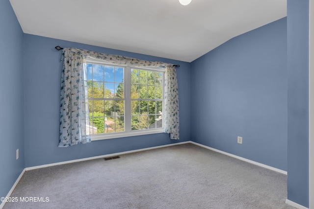 empty room featuring baseboards, visible vents, carpet, and vaulted ceiling