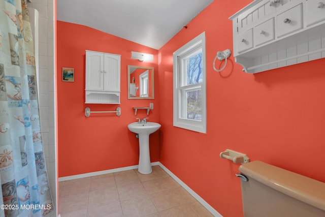 bathroom with tile patterned flooring, lofted ceiling, curtained shower, toilet, and baseboards