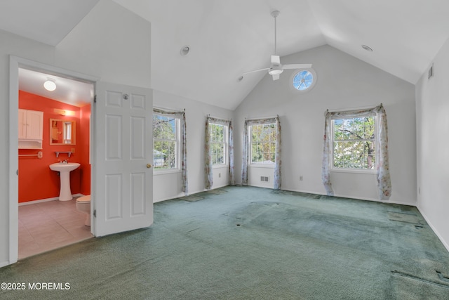 interior space with a sink, high vaulted ceiling, carpet, baseboards, and visible vents