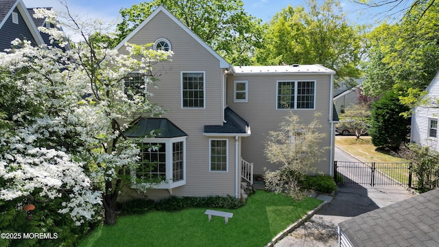 view of front of house with fence, a gate, a front lawn, and aphalt driveway