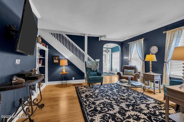 living room with baseboards, stairway, crown molding, arched walkways, and wood finished floors