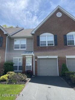 multi unit property featuring a garage, brick siding, and aphalt driveway