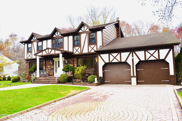 tudor house featuring stucco siding, a front lawn, a chimney, a shingled roof, and driveway