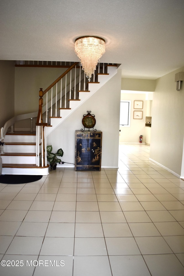 staircase featuring baseboards, an inviting chandelier, and tile patterned flooring