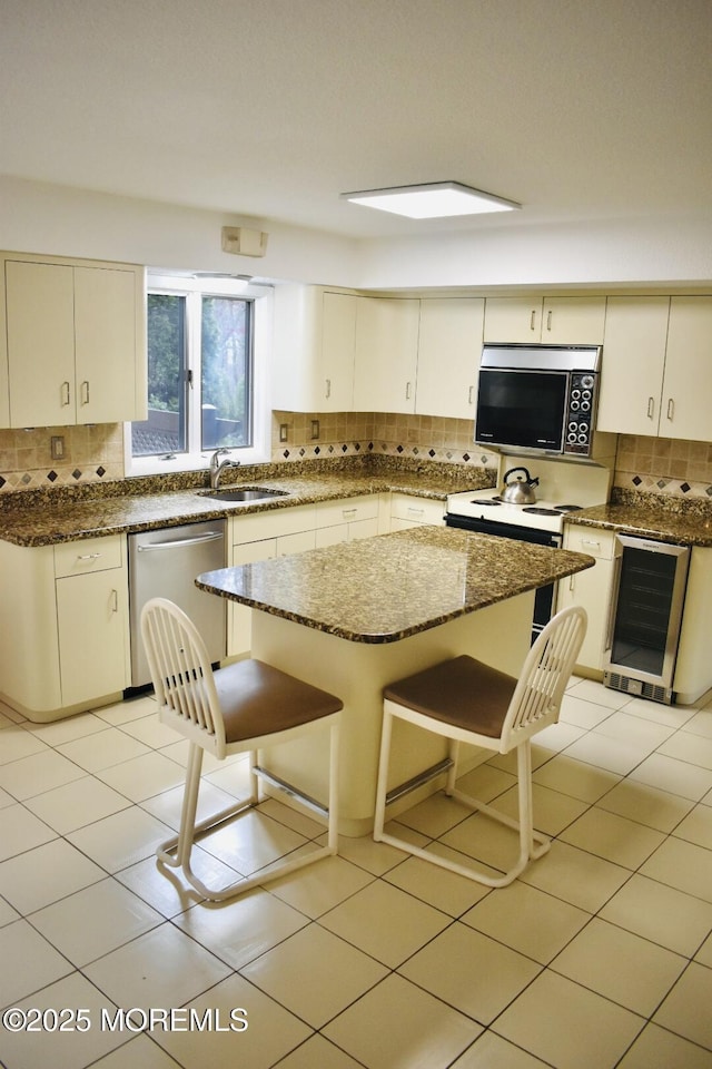 kitchen featuring wine cooler, dark stone counters, decorative backsplash, stainless steel dishwasher, and a sink