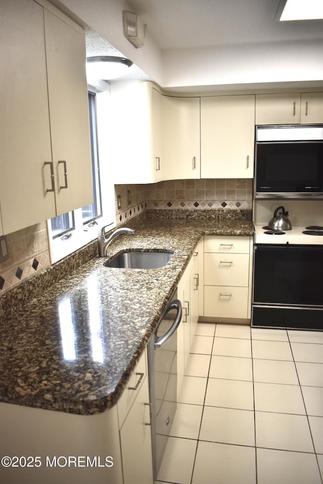 kitchen featuring tasteful backsplash, dishwasher, a sink, electric stove, and dark stone counters