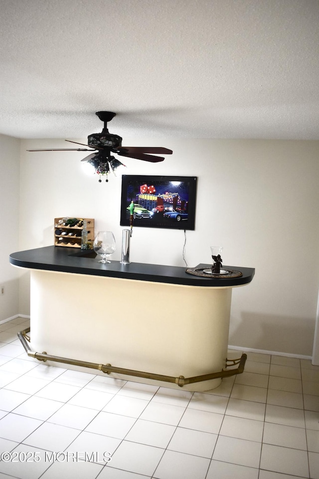 bar featuring a dry bar, baseboards, a textured ceiling, and a ceiling fan