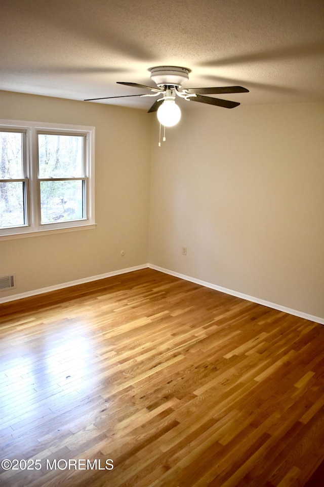 unfurnished room featuring ceiling fan, wood finished floors, and baseboards