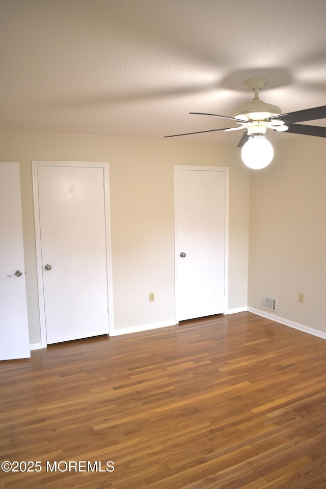 spare room featuring visible vents, baseboards, a ceiling fan, and wood finished floors