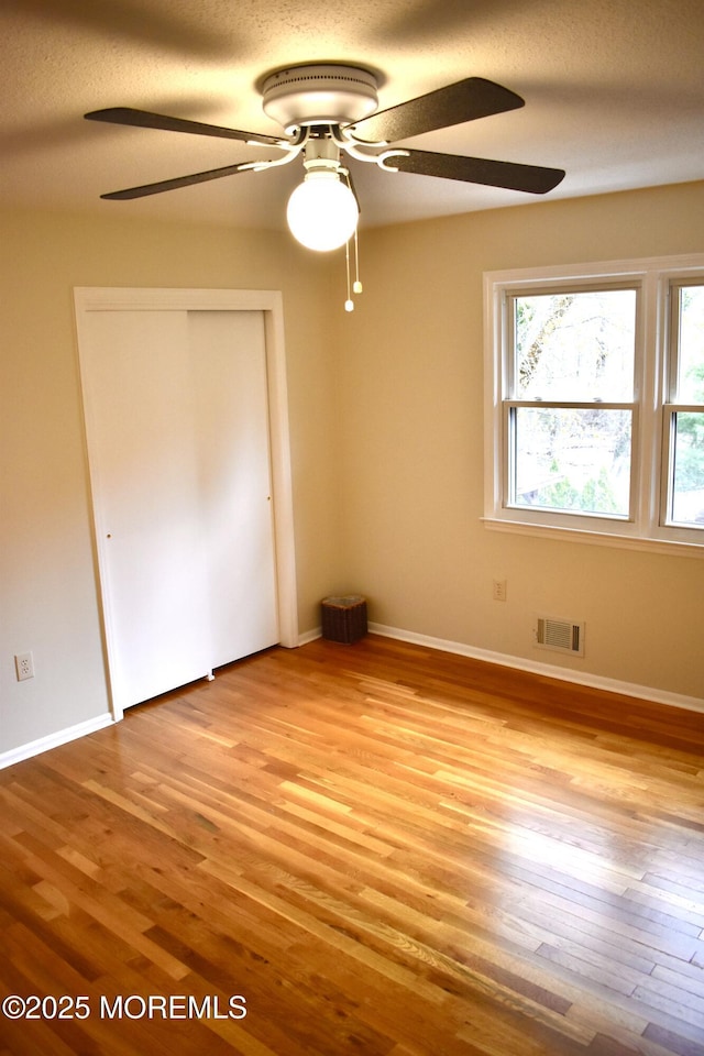 unfurnished bedroom featuring a closet, light wood finished floors, baseboards, and visible vents