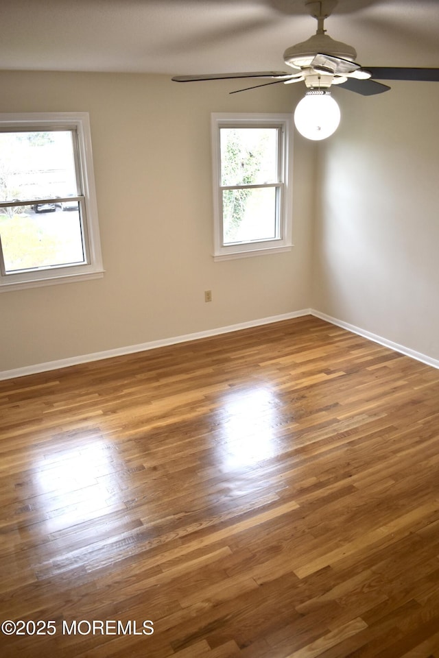 empty room with baseboards, a ceiling fan, and wood finished floors