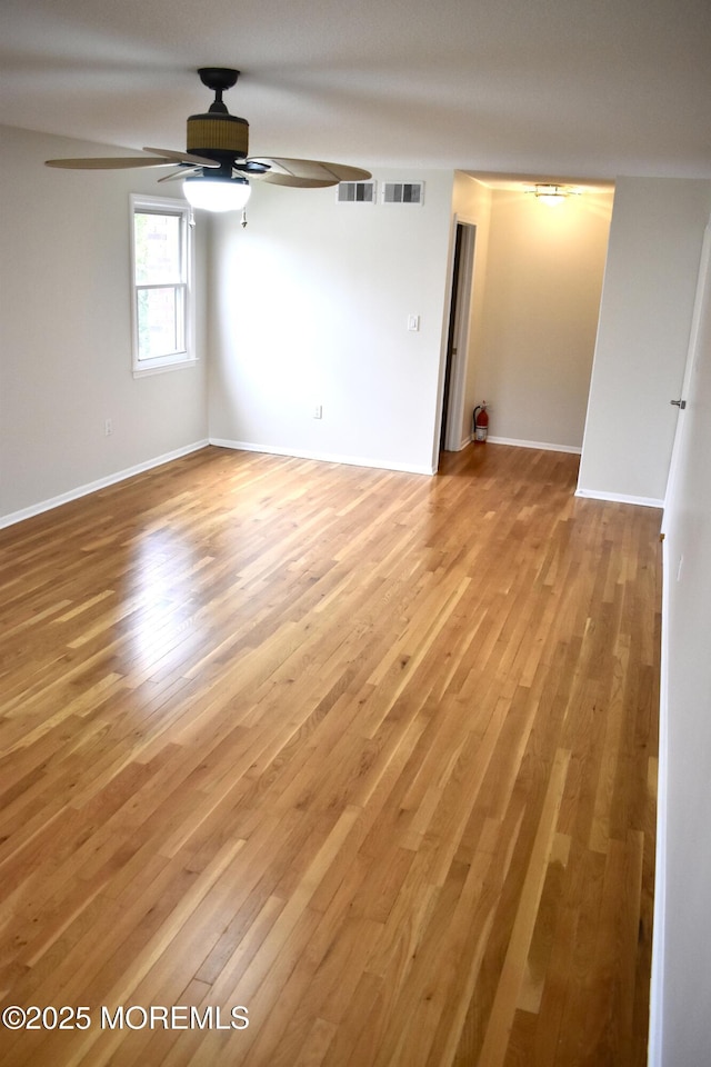spare room with light wood-style floors, ceiling fan, baseboards, and visible vents