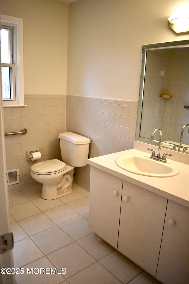 bathroom with vanity, tile patterned flooring, visible vents, and tile walls