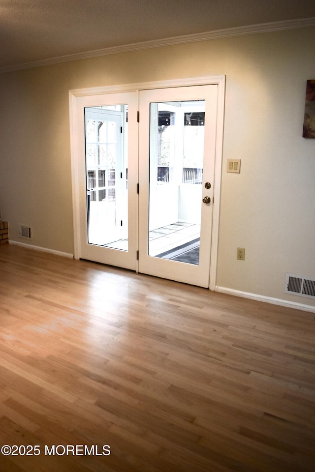 entryway with crown molding, baseboards, visible vents, and light wood-style floors