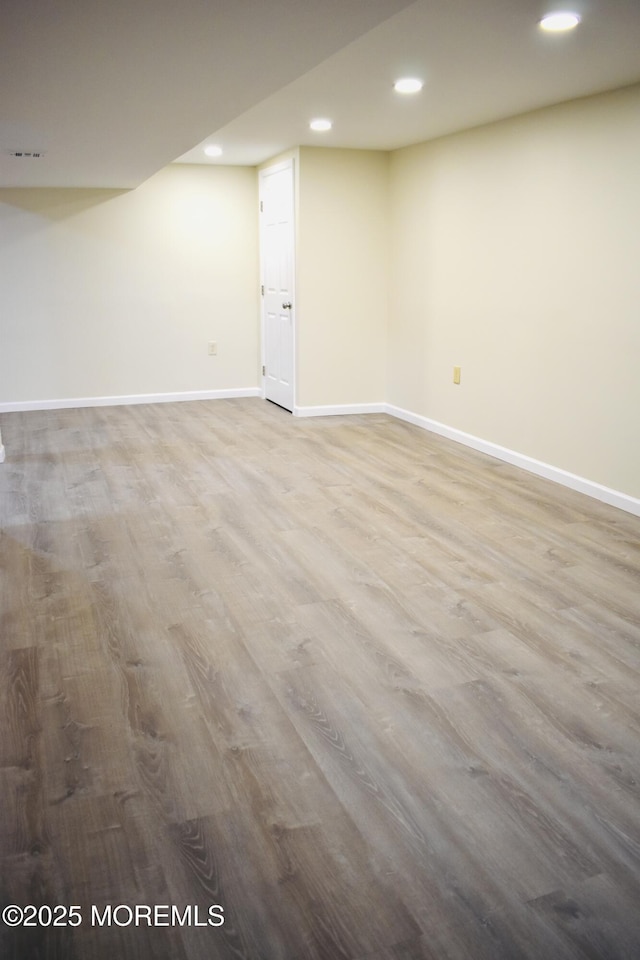 finished below grade area with visible vents, baseboards, recessed lighting, and wood finished floors
