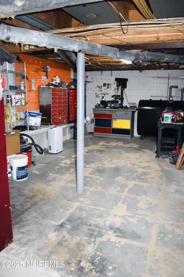 unfinished below grade area featuring heating fuel, a workshop area, and concrete block wall