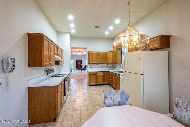 kitchen with a notable chandelier, recessed lighting, white appliances, under cabinet range hood, and brown cabinetry