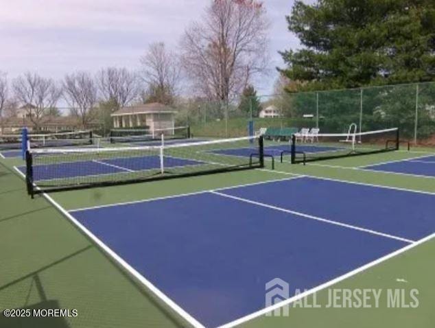 view of tennis court featuring community basketball court and fence