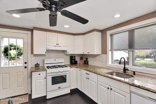 kitchen featuring tasteful backsplash, under cabinet range hood, a sink, and white appliances