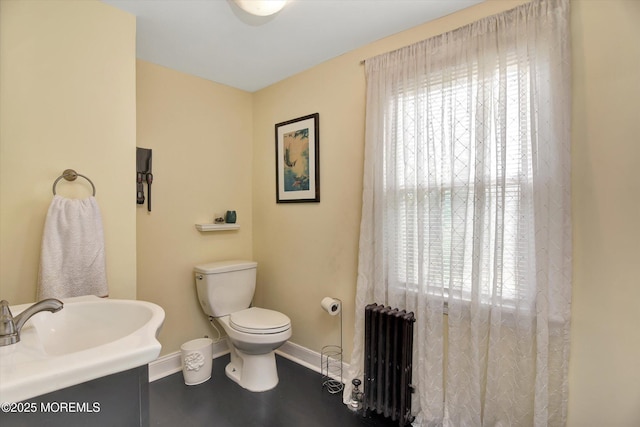 bathroom with toilet, vanity, baseboards, and radiator