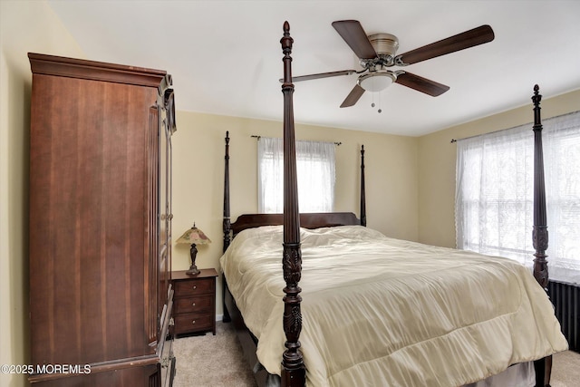 bedroom with multiple windows, light colored carpet, and a ceiling fan