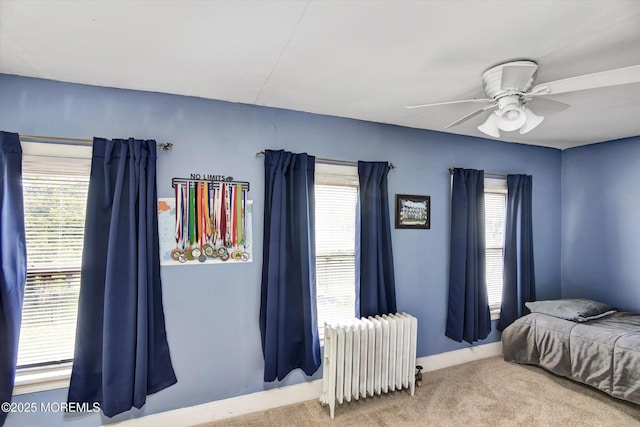 bedroom with carpet floors, baseboards, multiple windows, and radiator