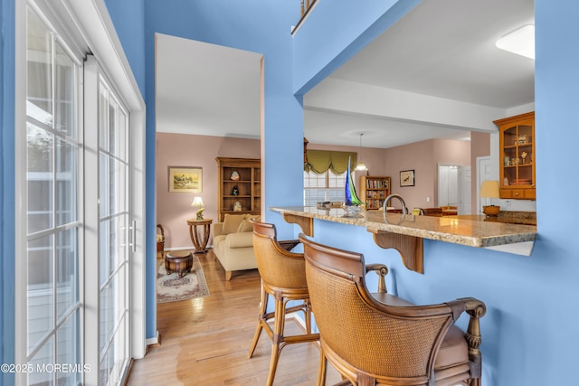 bar with pendant lighting, light wood-type flooring, and baseboards