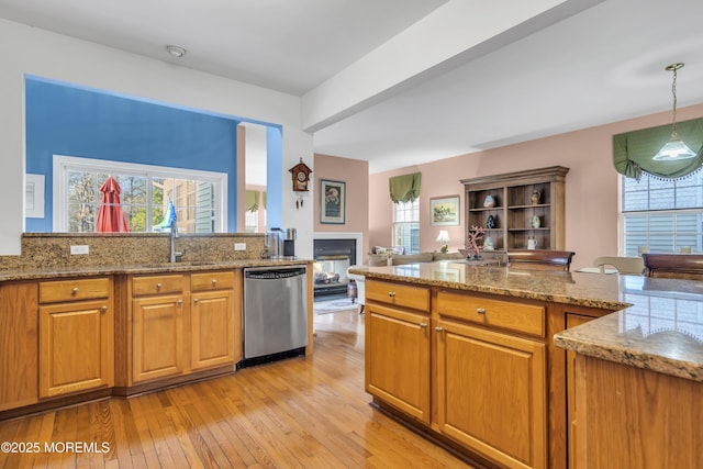 kitchen featuring light wood-style floors, brown cabinets, stainless steel dishwasher, and a sink